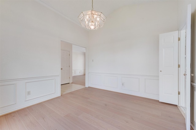 11275 Old Military Trl, Forney, TX 75126 - unfurnished room with a chandelier, a decorative wall, a wainscoted wall, light wood-style floors, and lofted ceiling