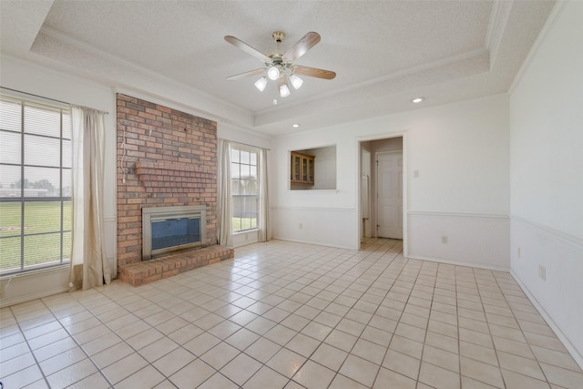 11275 Old Military Trl, Forney, TX 75126 - unfurnished living room featuring a tray ceiling, ceiling fan, ornamental molding, light tile patterned floors, and a fireplace