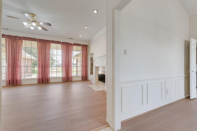 11275 Old Military Trl, Forney, TX 75126 - unfurnished living room with light wood-type flooring, a ceiling fan, crown molding, a high end fireplace, and a textured ceiling