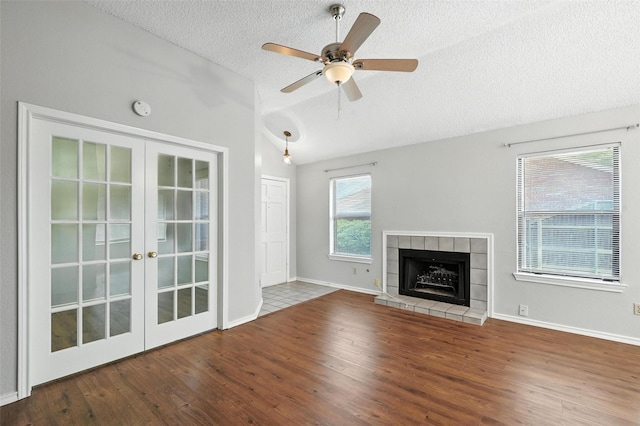 1450 Hampton Rd, Grapevine, TX 76051 - unfurnished living room featuring vaulted ceiling, wood finished floors, french doors, a textured ceiling, and a tile fireplace