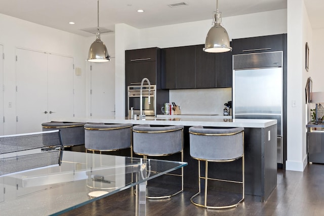 2200 Victory Ave Unit 1105, Dallas, TX 75219 - kitchen featuring built in fridge, hanging light fixtures, dark wood-style flooring, a breakfast bar area, and dark cabinets