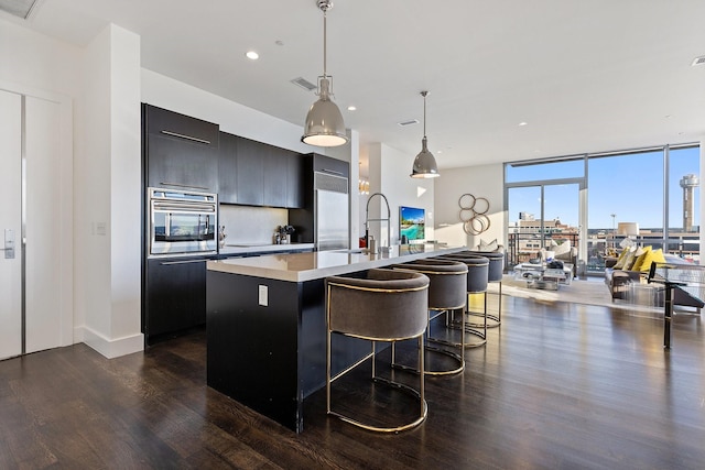 2200 Victory Ave Unit 1105, Dallas, TX 75219 - kitchen featuring dark wood finished floors, a center island with sink, expansive windows, light countertops, and modern cabinets