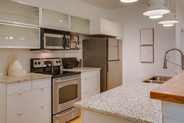 1111 S Akard St Unit 310, Dallas, TX 75215 - kitchen featuring stainless steel appliances, backsplash, light stone countertops, and white cabinetry