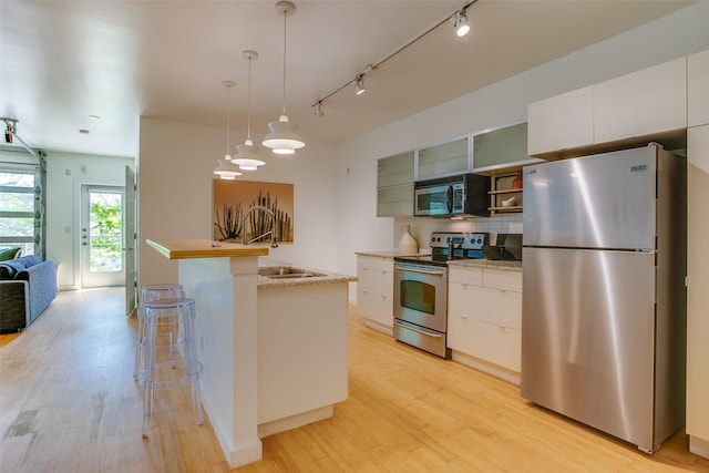 1111 S Akard St Unit 310, Dallas, TX 75215 - kitchen with stainless steel appliances, light wood-style flooring, a breakfast bar area, and white cabinetry