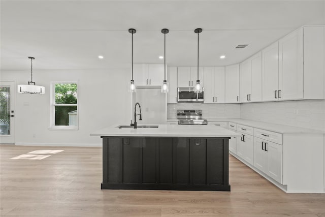 812 Sylvan Dr, Garland, TX 75040 - kitchen featuring appliances with stainless steel finishes, backsplash, light wood-style floors, white cabinetry, and recessed lighting