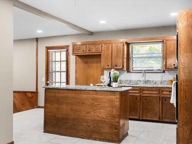 4108 Grand Lake Dr, Lake Worth, TX 76135 - kitchen with a center island, brown cabinetry, recessed lighting, light stone counters, and tasteful backsplash