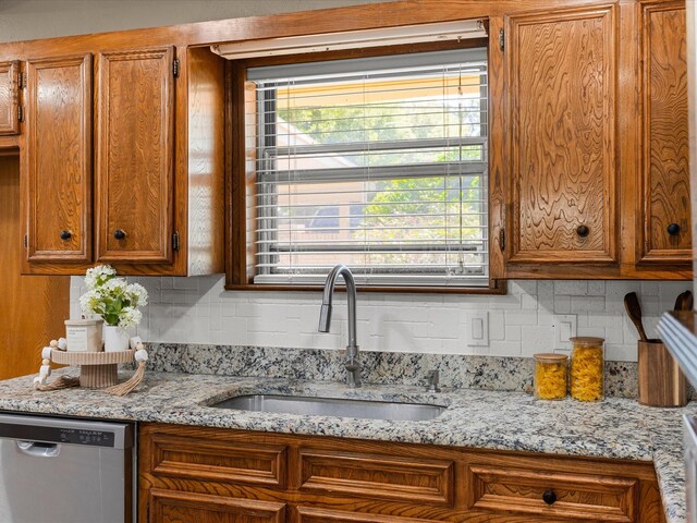 4108 Grand Lake Dr, Lake Worth, TX 76135 - kitchen with stainless steel dishwasher, brown cabinets, decorative backsplash, and light stone countertops