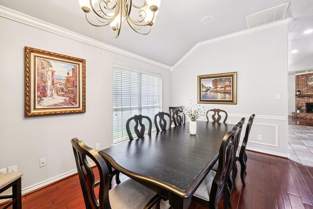 8700 Blacktail Trl, Mckinney, TX 75070 - dining space with a chandelier, hardwood / wood-style floors, vaulted ceiling, crown molding, and a brick fireplace