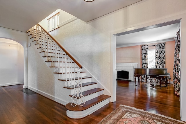 6224 Curzon Ave, Fort Worth, TX 76116 - stairway featuring arched walkways, wood finished floors, a brick fireplace, and ornamental molding
