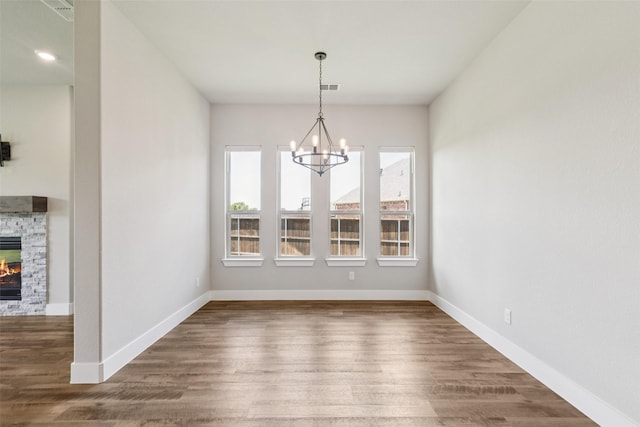 7709 Potter St, Rowlett, TX 75089 - unfurnished dining area with a chandelier, a stone fireplace, and dark wood-style flooring