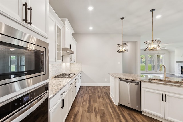 7709 Potter St, Rowlett, TX 75089 - kitchen featuring appliances with stainless steel finishes, tasteful backsplash, light stone counters, white cabinetry, and dark wood-style floors