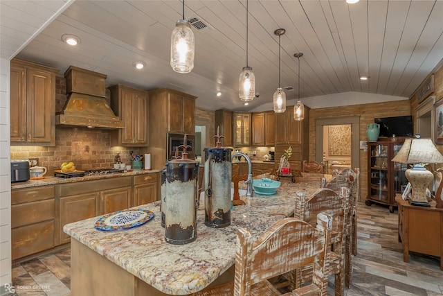 9900 Myrtis Texas Line Rd, Vivian, LA 71082 - kitchen with custom range hood, brown cabinetry, lofted ceiling, light stone countertops, and recessed lighting