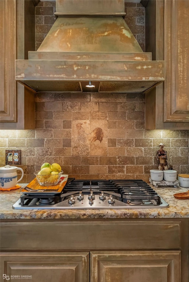 9900 Myrtis Texas Line Rd, Vivian, LA 71082 - kitchen view of premium range hood, decorative backsplash, stainless steel gas stovetop, and light stone countertops