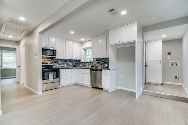 331 Andover Dr, Mesquite, TX 75149 - kitchen with appliances with stainless steel finishes, dark countertops, backsplash, white cabinets, and light wood-type flooring