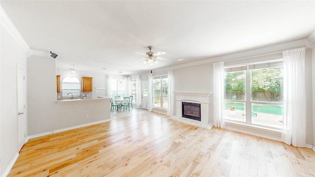 4009 Bickmore Ln, Fort Worth, TX 76244 - unfurnished living room featuring light wood-type flooring, a ceiling fan, ornamental molding, and a glass covered fireplace
