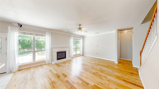 4009 Bickmore Ln, Fort Worth, TX 76244 - unfurnished living room featuring light wood-type flooring, a high end fireplace, stairs, a ceiling fan, and ornamental molding