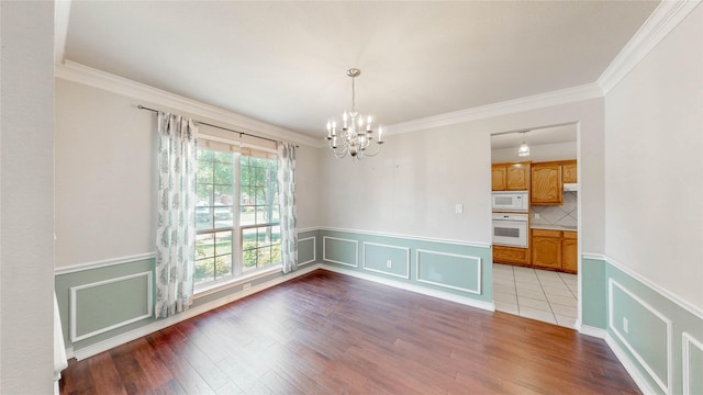 4009 Bickmore Ln, Fort Worth, TX 76244 - unfurnished dining area with a chandelier, crown molding, wainscoting, wood finished floors, and a decorative wall