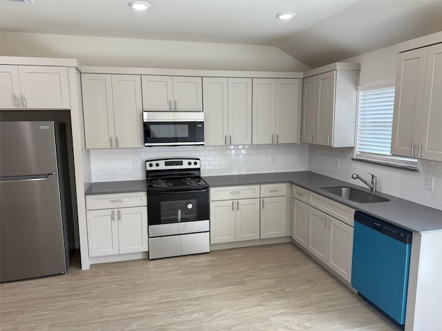 1803 Boxwood Dr, Sherman, TX 75092 - kitchen with stainless steel appliances, lofted ceiling, dark countertops, light wood-type flooring, and backsplash