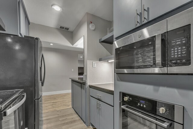 2020 Skylark Dr, Dallas, TX 75216 - kitchen featuring appliances with stainless steel finishes, dark countertops, open shelves, gray cabinetry, and light wood-style flooring