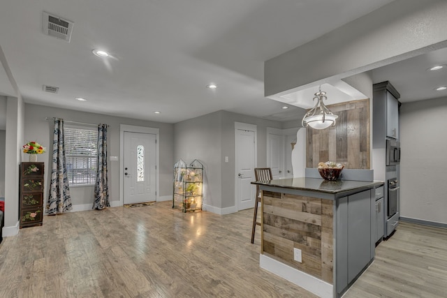2020 Skylark Dr, Dallas, TX 75216 - kitchen with light wood-type flooring, recessed lighting, gray cabinetry, hanging light fixtures, and stainless steel microwave
