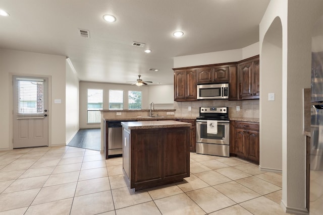 3228 Buckthorn Ln, Denton, TX 76226 - kitchen with stainless steel appliances, decorative backsplash, a peninsula, a ceiling fan, and a kitchen island