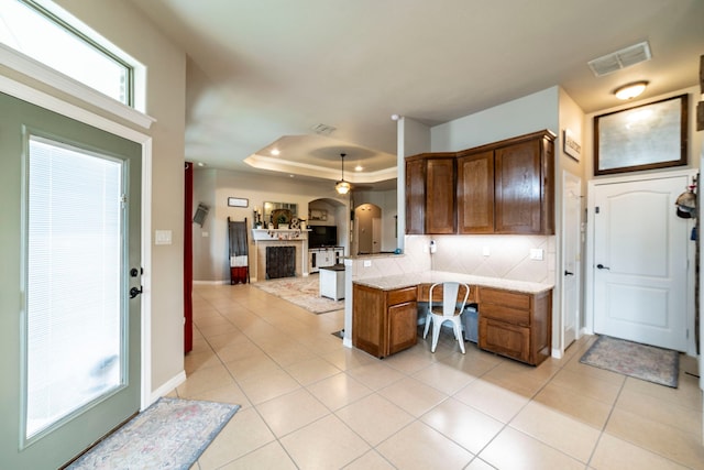 5872 Nathaniel Dr, Fort Worth, TX 76179 - kitchen featuring arched walkways, open floor plan, built in desk, light tile patterned floors, and brown cabinets