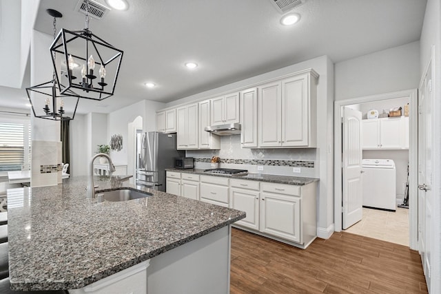 3804 Driftwood Ln, Northlake, TX 76226 - kitchen featuring washer / dryer, appliances with stainless steel finishes, under cabinet range hood, arched walkways, and backsplash