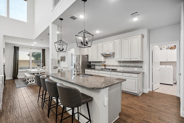 3804 Driftwood Ln, Northlake, TX 76226 - kitchen featuring washer / clothes dryer, stainless steel appliances, under cabinet range hood, and dark wood finished floors