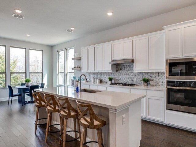 2112 Deer Run, Gunter, TX 75058 - kitchen featuring stainless steel appliances, light countertops, backsplash, dark wood-style flooring, and under cabinet range hood
