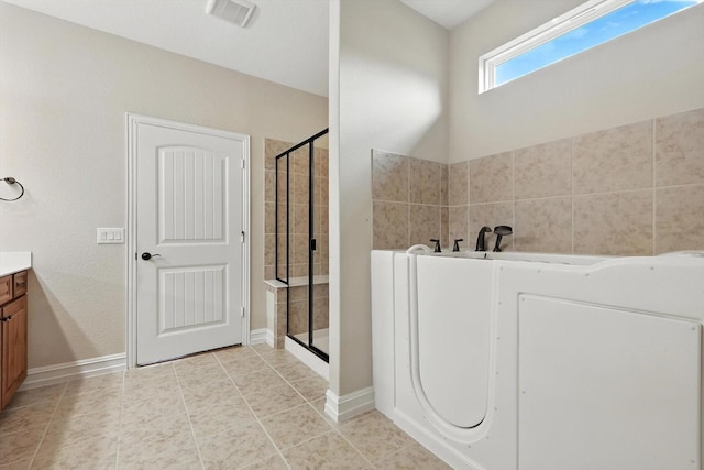 6371 Walnut Hill Ct, Frisco, TX 75036 - bathroom with washer / dryer, vanity, a shower stall, a garden tub, and tile patterned flooring