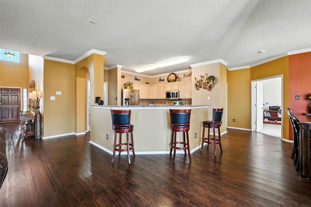 1906 Walnut Hills Ln, Mansfield, TX 76063 - kitchen featuring stainless steel appliances, dark wood finished floors, a breakfast bar area, a textured ceiling, and a peninsula