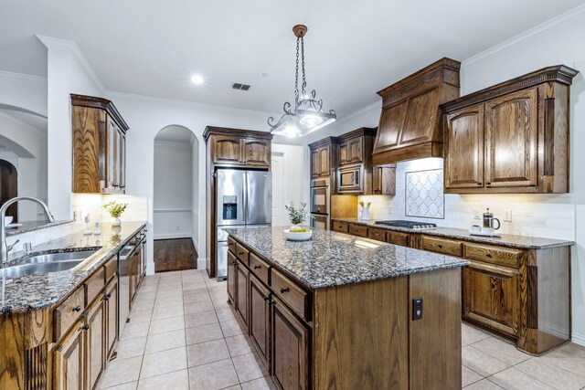 4205 Midpark Ln, Plano, TX 75074 - kitchen with appliances with stainless steel finishes, arched walkways, dark stone countertops, light tile patterned floors, and crown molding