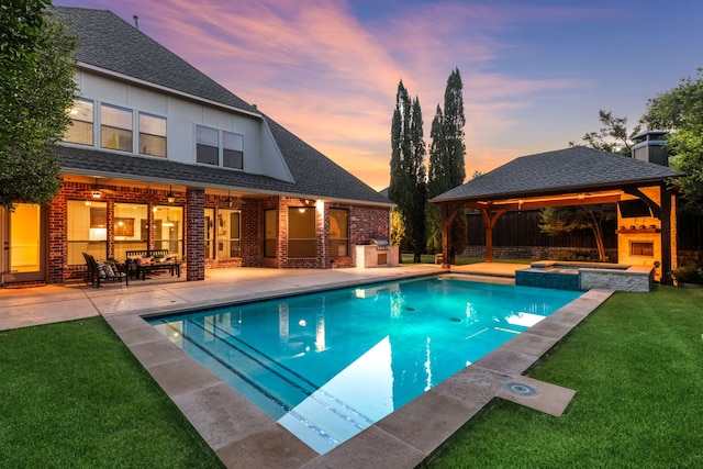 4205 Midpark Ln, Plano, TX 75074 - pool at dusk with a gazebo, a fireplace, a patio area, a yard, and a pool with connected hot tub