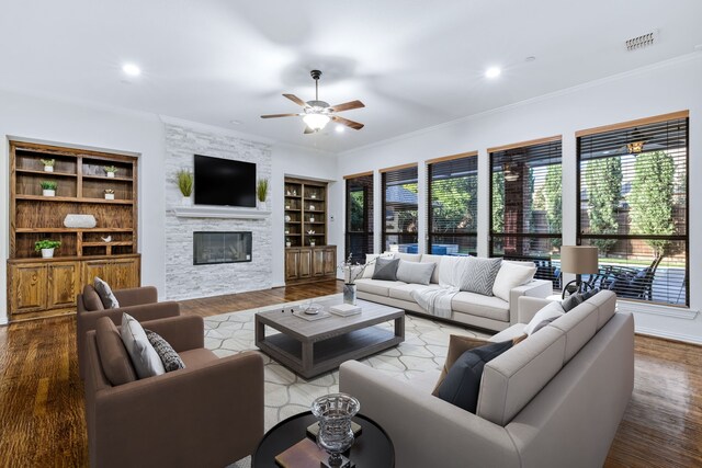 4205 Midpark Ln, Plano, TX 75074 - living room featuring a stone fireplace, a ceiling fan, ornamental molding, wood finished floors, and recessed lighting