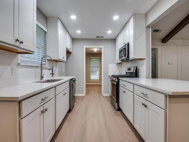 1044 Peach Ln, Desoto, TX 75115 - kitchen featuring stainless steel appliances, tasteful backsplash, light wood-style flooring, a peninsula, and recessed lighting