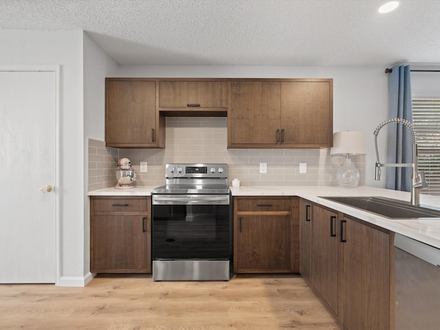 1545 Knottingham Dr, Little Elm, TX 75068 - kitchen featuring appliances with stainless steel finishes, light countertops, light wood finished floors, decorative backsplash, and a textured ceiling