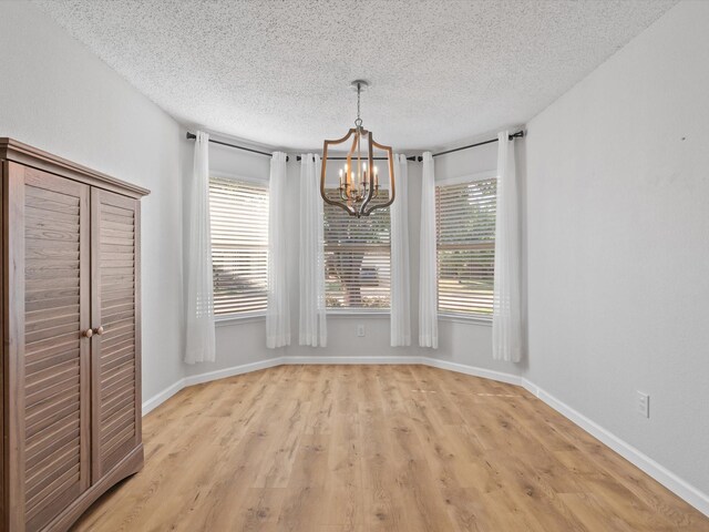 1545 Knottingham Dr, Little Elm, TX 75068 - unfurnished dining area featuring a chandelier, a textured ceiling, and light wood-type flooring