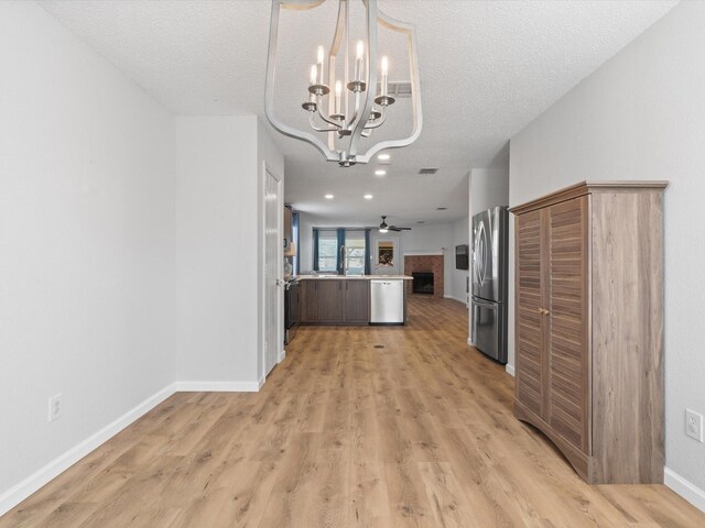 1545 Knottingham Dr, Little Elm, TX 75068 - kitchen with stainless steel appliances, open floor plan, a chandelier, a peninsula, and light wood-style floors