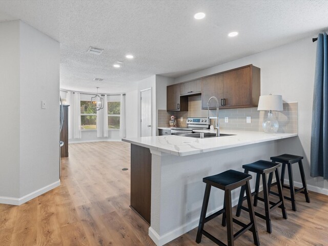 1545 Knottingham Dr, Little Elm, TX 75068 - kitchen with a textured ceiling, recessed lighting, backsplash, a peninsula, and a breakfast bar area