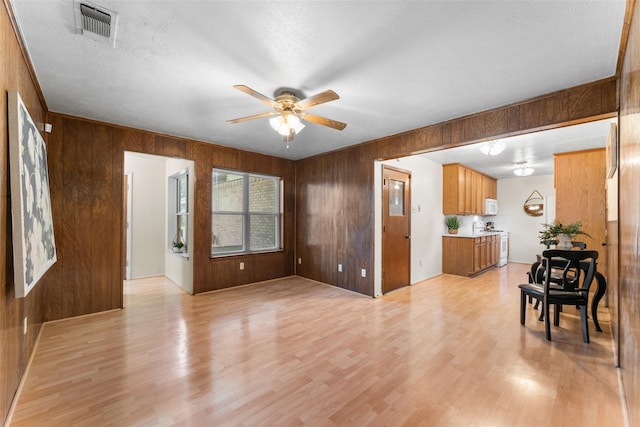 1238 Caladium Dr, Mesquite, TX 75149 - living room featuring wood walls, ceiling fan, light wood-style flooring, and a textured ceiling
