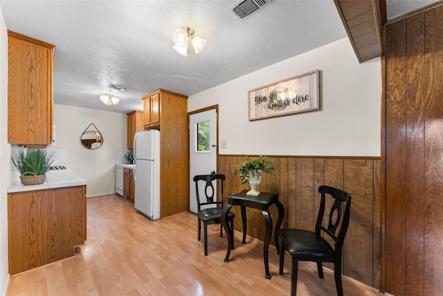 1238 Caladium Dr, Mesquite, TX 75149 - kitchen featuring white appliances, light countertops, light wood finished floors, wainscoting, and brown cabinets