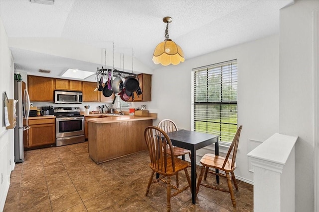 4900 Highbank Dr, Arlington, TX 76018 - kitchen with stainless steel appliances, vaulted ceiling, a peninsula, brown cabinets, and light countertops