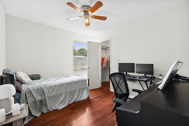 4900 Highbank Dr, Arlington, TX 76018 - bedroom with dark wood-type flooring, a desk, a walk in closet, a textured ceiling, and a ceiling fan