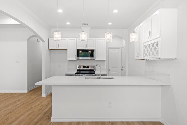 301 Henry St, Waxahachie, TX 75165 - kitchen featuring appliances with stainless steel finishes, arched walkways, light wood finished floors, white cabinetry, and light countertops