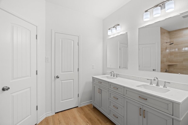 301 Henry St, Waxahachie, TX 75165 - full bathroom with double vanity, wood finished floors, and a tile shower