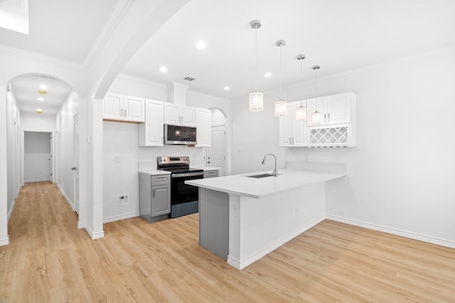 301 Henry St, Waxahachie, TX 75165 - kitchen with appliances with stainless steel finishes, a peninsula, light countertops, white cabinets, and crown molding