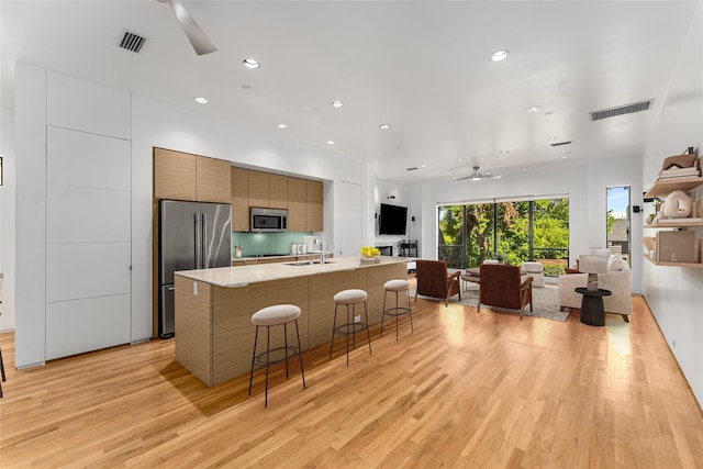 1505 N Haskell Ave Unit 5, Dallas, TX 75204 - kitchen featuring appliances with stainless steel finishes, ceiling fan, modern cabinets, light wood finished floors, and a kitchen breakfast bar