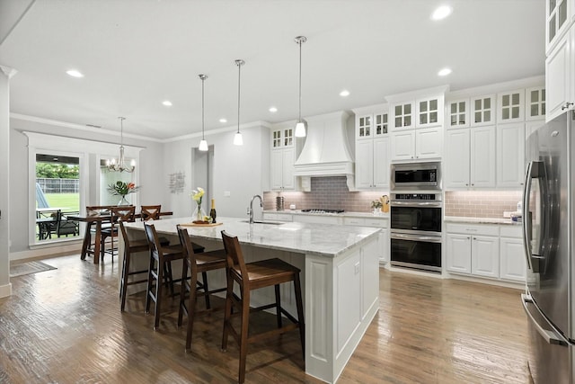 2941 American Sparrow Dr, Midlothian, TX 76065 - kitchen with custom range hood, appliances with stainless steel finishes, decorative backsplash, ornamental molding, and a center island with sink