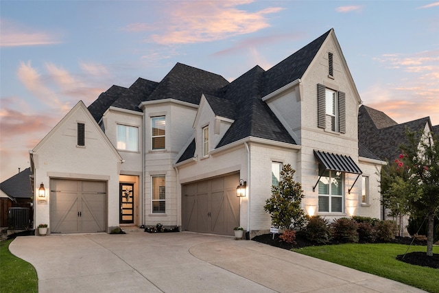 2217 Grey September St, Celina, TX 75009 - french country style house featuring driveway, a shingled roof, brick siding, a front lawn, and a garage