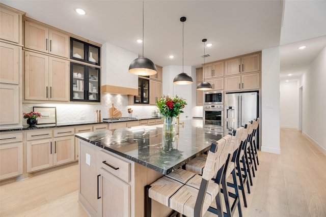 2217 Grey September St, Celina, TX 75009 - kitchen featuring appliances with stainless steel finishes, a spacious island, tasteful backsplash, light brown cabinets, and a kitchen bar